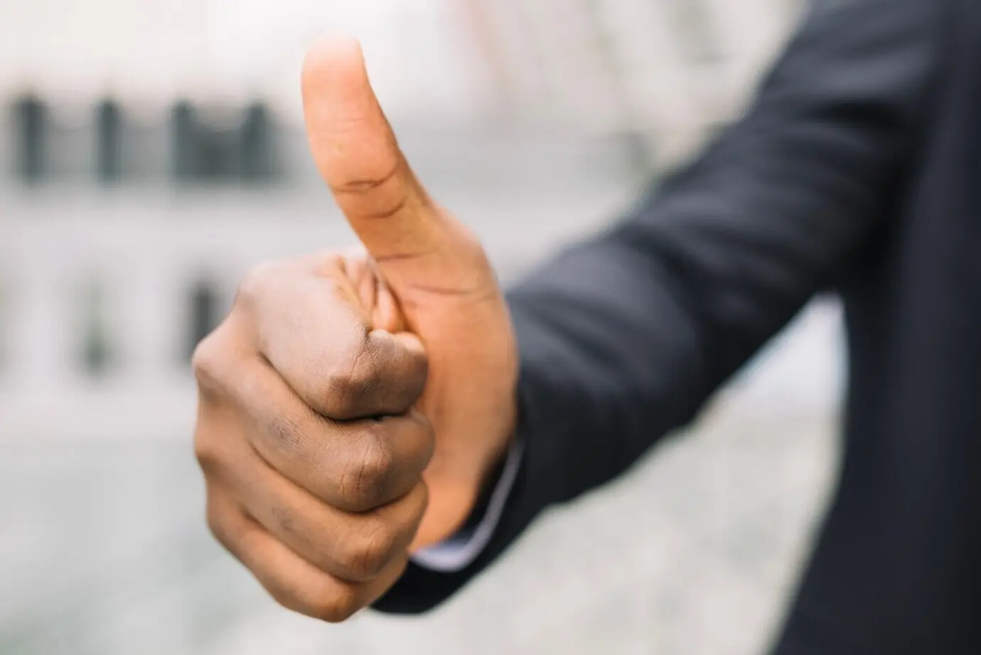 Обрезанный кадр мужчины, показывающего большой палец вверх.